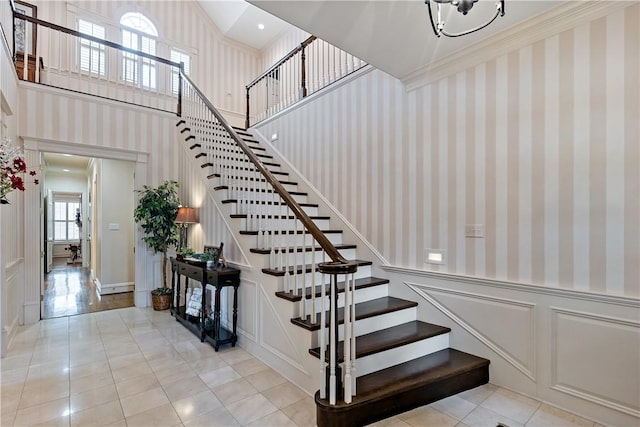 stairway with a high ceiling, ornamental molding, and tile patterned flooring