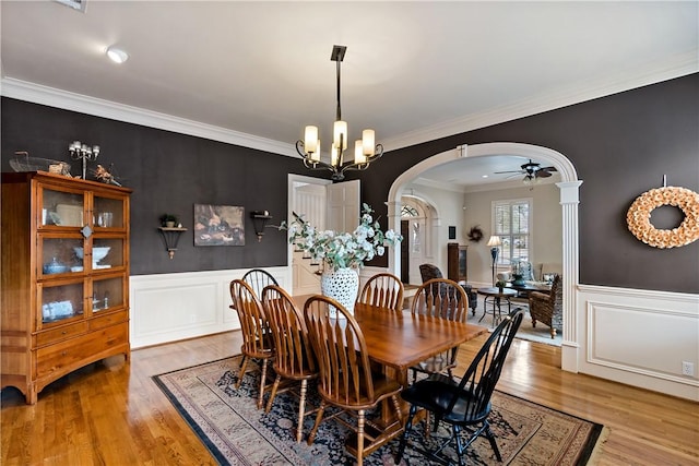 dining room with ornamental molding, ceiling fan with notable chandelier, and light wood-type flooring