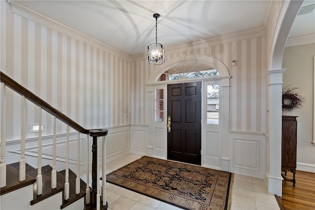 foyer with an inviting chandelier, light tile patterned floors, and ornamental molding