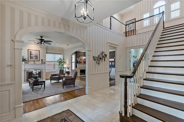 tiled entrance foyer featuring ornamental molding and ceiling fan with notable chandelier