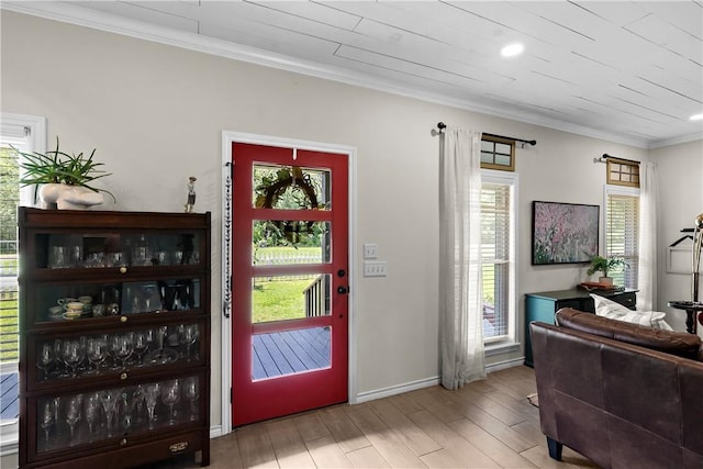 foyer with crown molding, wood finished floors, baseboards, and a healthy amount of sunlight