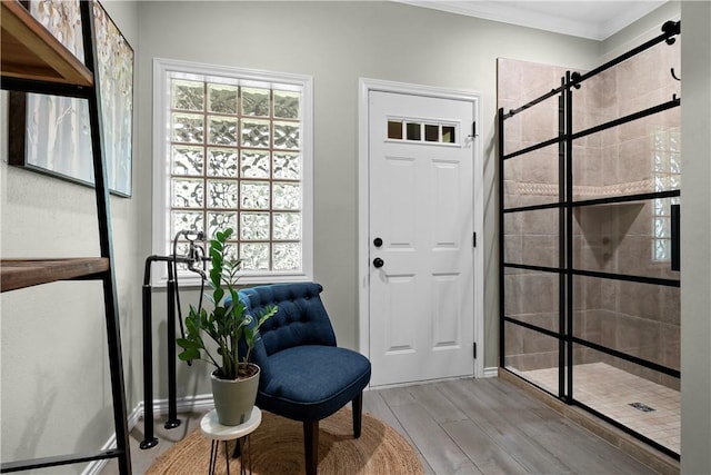 sitting room with ornamental molding, a wealth of natural light, a barn door, and wood finished floors