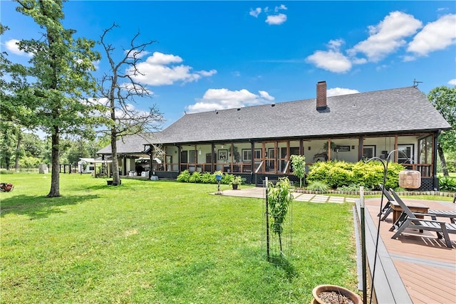 back of property with a yard, a chimney, and a shingled roof