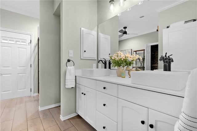 full bathroom with a sink, ceiling fan, double vanity, and baseboards