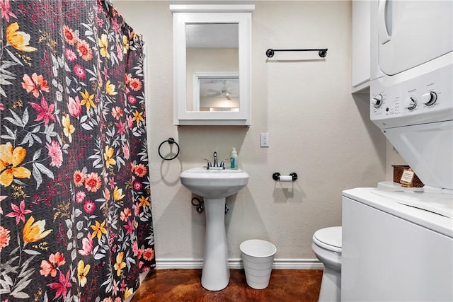 full bathroom featuring a shower with curtain, toilet, stacked washer and dryer, and baseboards