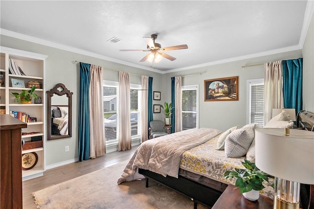 bedroom with ornamental molding, visible vents, and wood finished floors