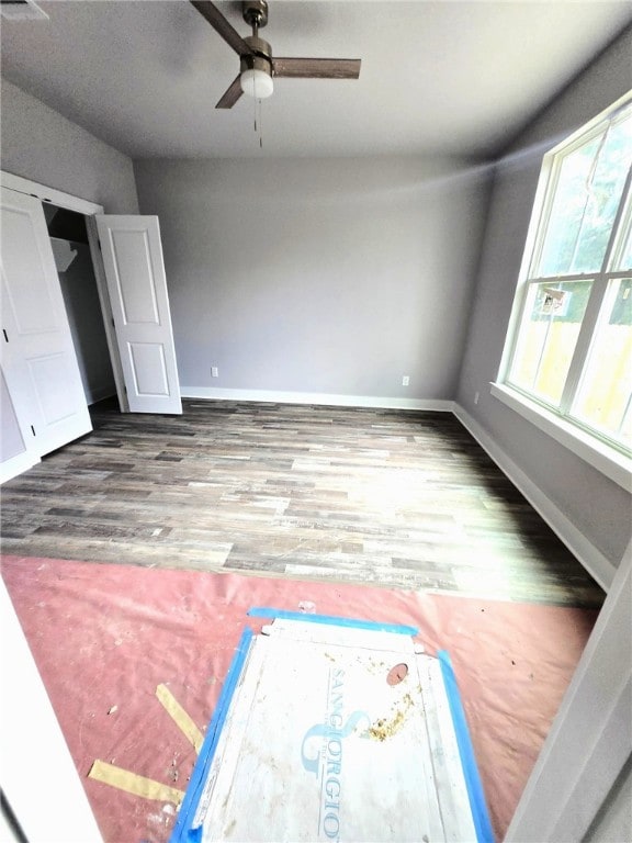 interior space with a ceiling fan, baseboards, and wood finished floors