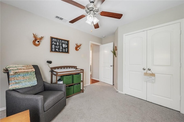 sitting room with visible vents, baseboards, light colored carpet, and a ceiling fan