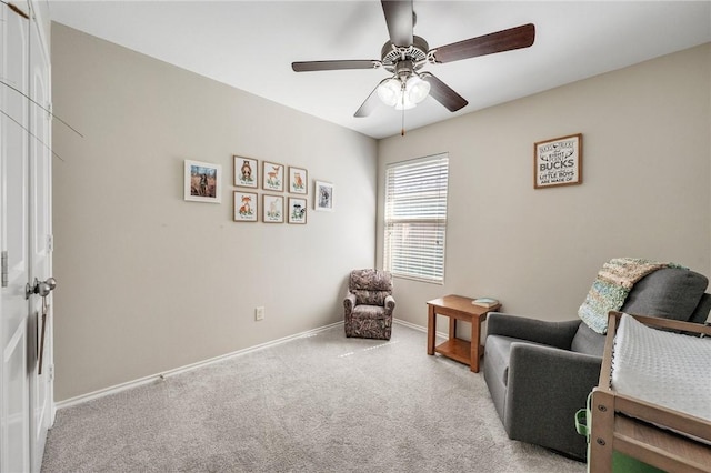 sitting room featuring baseboards, carpet floors, and a ceiling fan