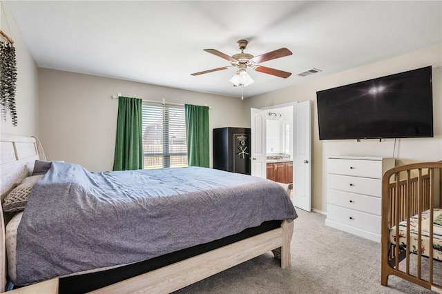 carpeted bedroom featuring ensuite bath, a ceiling fan, and visible vents