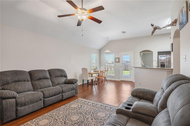 living room featuring visible vents, wood finished floors, baseboards, lofted ceiling, and ceiling fan