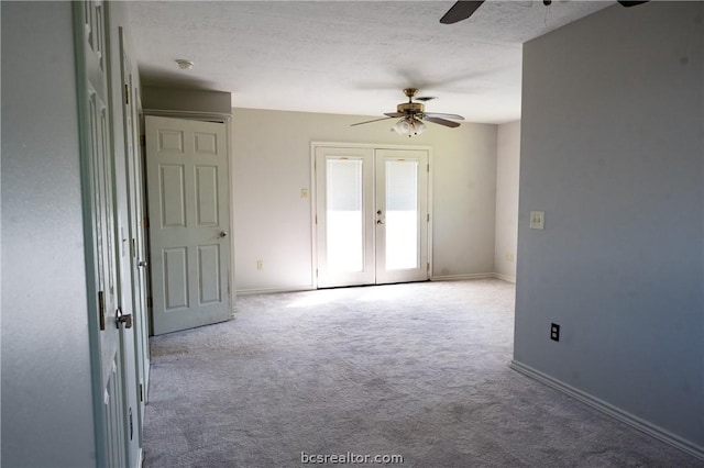 carpeted empty room with ceiling fan, a textured ceiling, and french doors