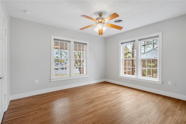 empty room featuring ceiling fan, light wood-type flooring, and a wealth of natural light