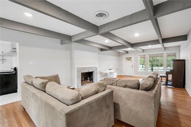 living room with beam ceiling, a fireplace, and light wood-type flooring