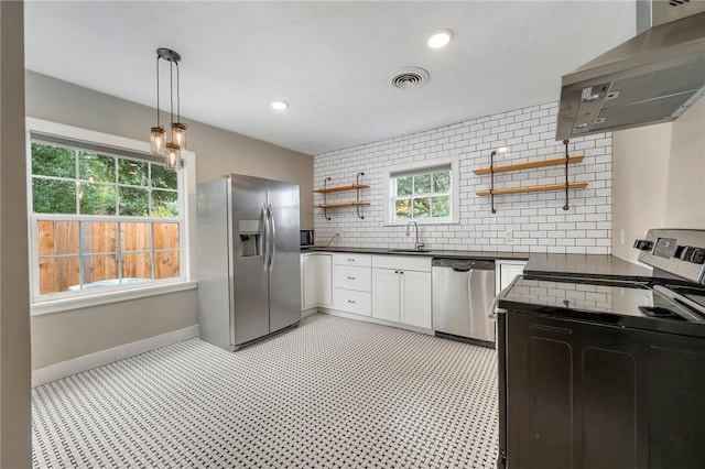 kitchen featuring plenty of natural light, white cabinets, range hood, and appliances with stainless steel finishes