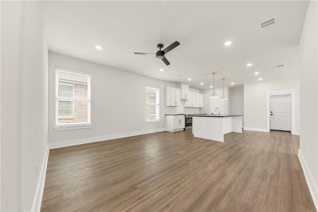 unfurnished living room featuring hardwood / wood-style floors, sink, and ceiling fan