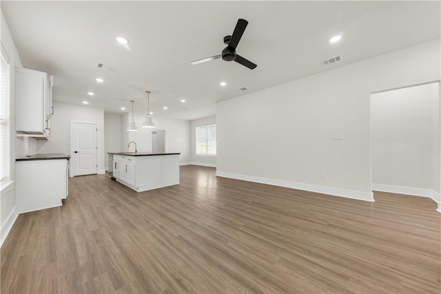 unfurnished living room with ceiling fan, sink, and light hardwood / wood-style floors