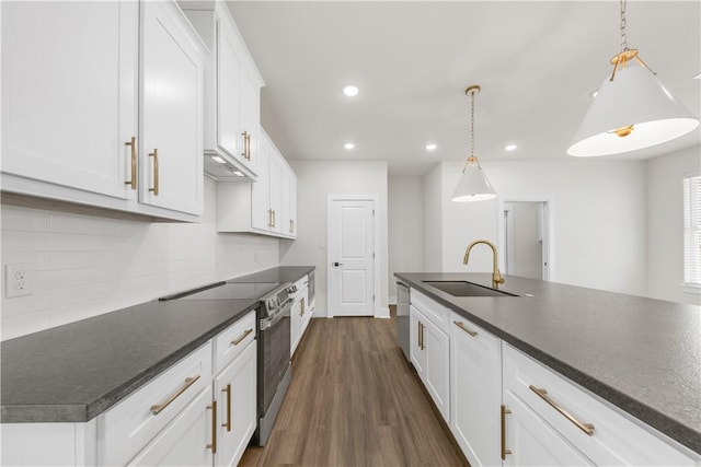 kitchen with sink, decorative light fixtures, a center island with sink, stainless steel appliances, and white cabinets