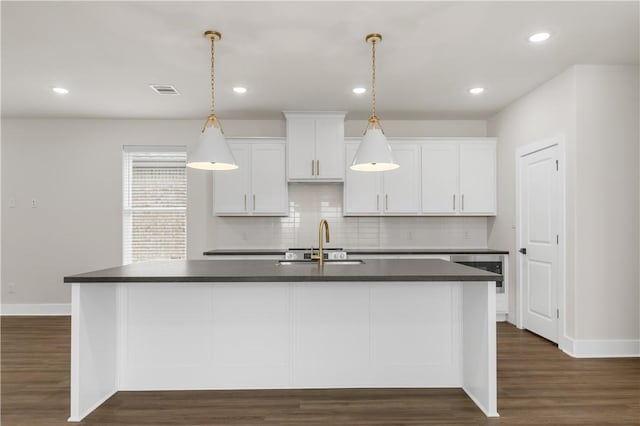 kitchen featuring a kitchen island with sink, sink, white cabinetry, and hanging light fixtures