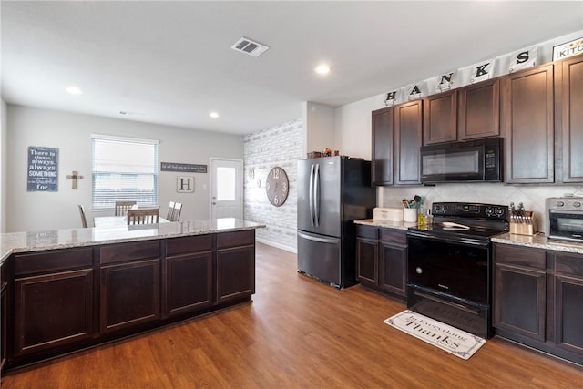974 Marquis Dr, Bryan, TX 77803 - kitchen featuring black appliances, wood finished floors, dark brown cabinets, light stone countertops, and recessed lighting