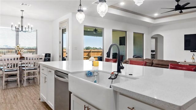 kitchen with white cabinets, a wealth of natural light, stainless steel dishwasher, and hanging light fixtures