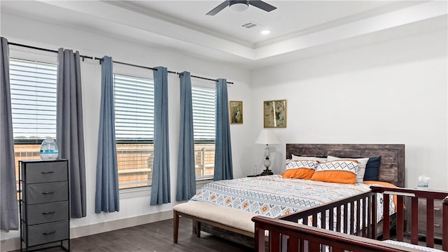 bedroom with multiple windows, dark hardwood / wood-style flooring, a raised ceiling, and ceiling fan