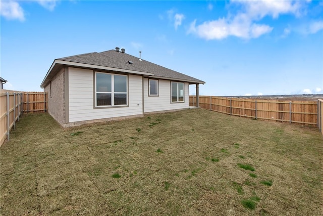 back of house featuring a shingled roof, a lawn, and a fenced backyard