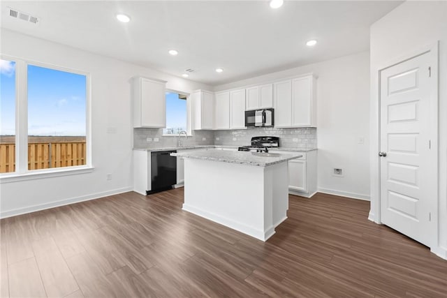 kitchen with a center island, white cabinets, black appliances, and light stone countertops