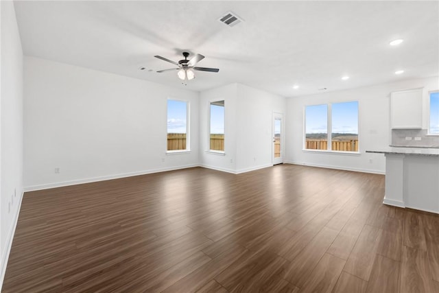 unfurnished living room featuring a ceiling fan, visible vents, dark wood finished floors, and baseboards