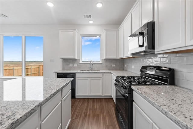 kitchen with light stone counters, a sink, visible vents, white cabinetry, and black appliances