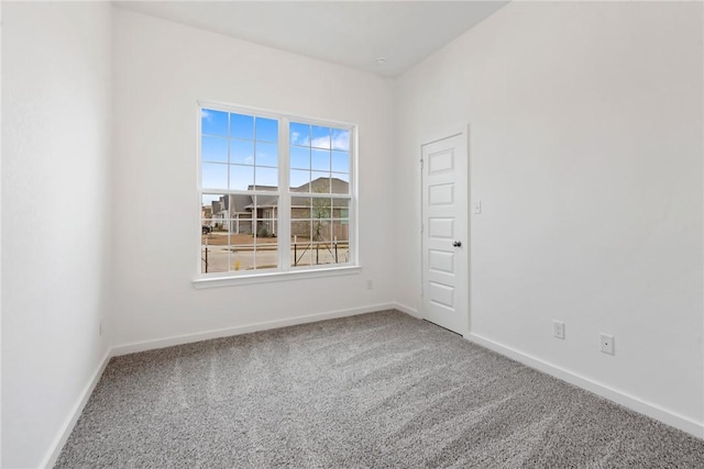 carpeted empty room featuring baseboards