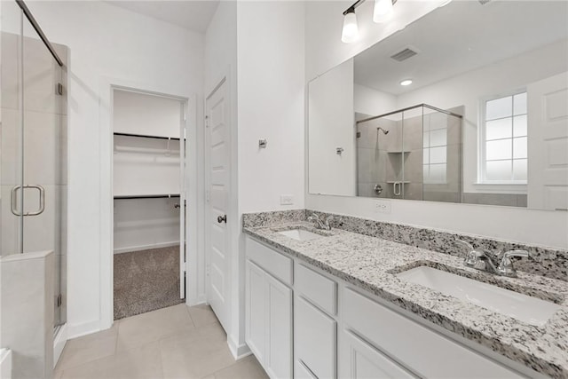 full bath featuring a stall shower, a spacious closet, a sink, and tile patterned floors