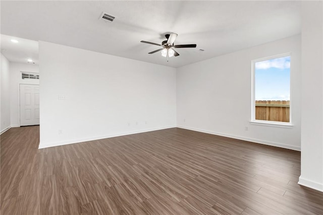 spare room with baseboards, ceiling fan, visible vents, and dark wood-style flooring