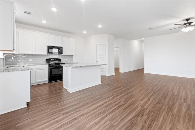 kitchen with open floor plan, a center island, black appliances, white cabinetry, and a sink