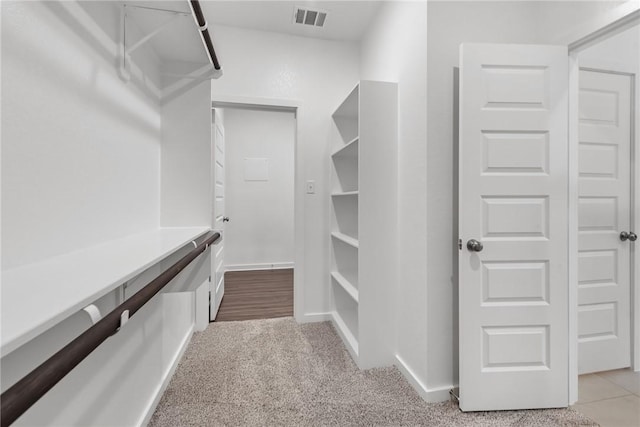 spacious closet with light colored carpet and visible vents