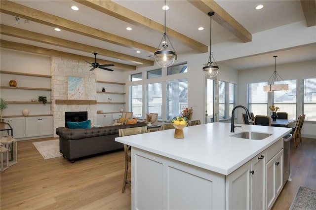 kitchen featuring sink, hanging light fixtures, a center island with sink, light hardwood / wood-style floors, and white cabinets