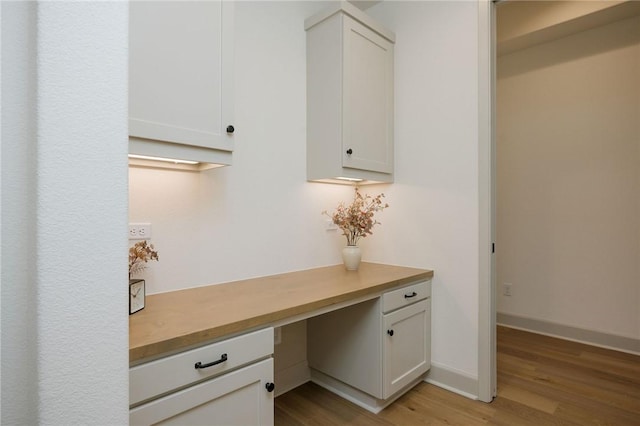 unfurnished office featuring built in desk and light wood-type flooring