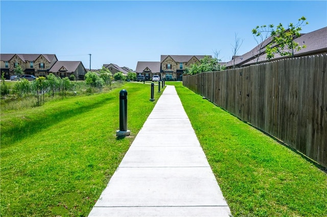 view of community featuring a residential view, fence, and a lawn