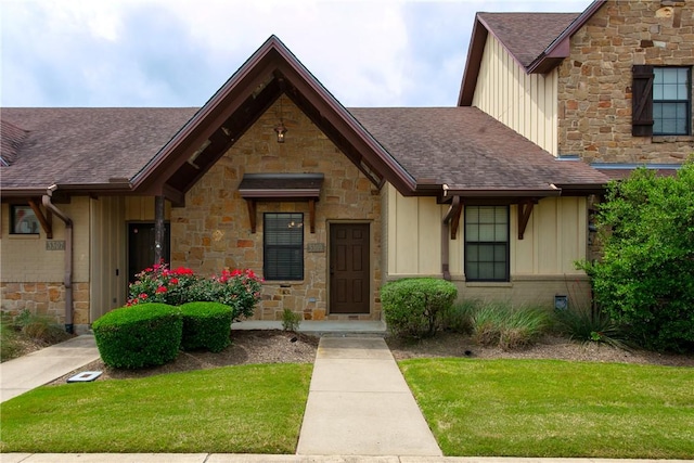 view of front of property with board and batten siding, a front yard, and a shingled roof