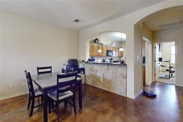 dining room featuring arched walkways, visible vents, concrete floors, and baseboards