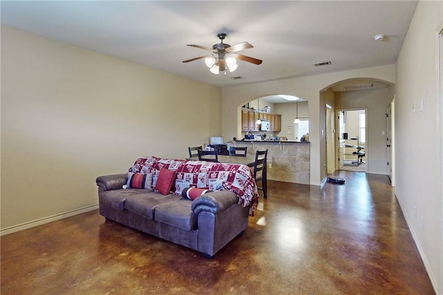 living room with visible vents, arched walkways, concrete flooring, and baseboards