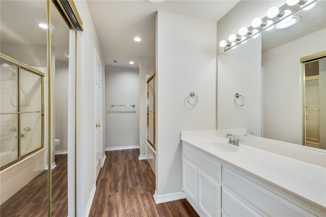 bathroom with toilet, shower / bath combination with glass door, wood finished floors, and vanity