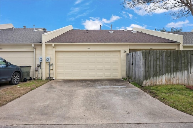 garage featuring driveway and fence