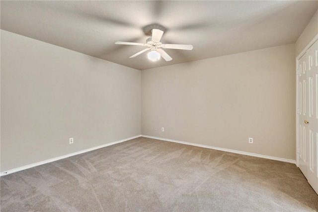 carpeted empty room featuring baseboards and a ceiling fan