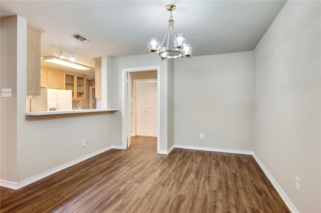 unfurnished dining area featuring a notable chandelier, wood finished floors, visible vents, and baseboards