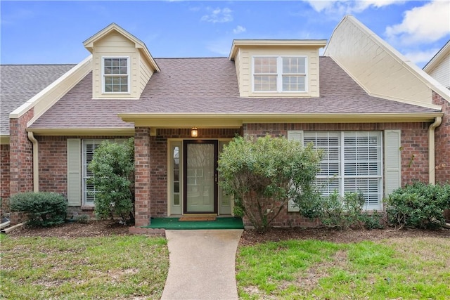 view of front of home featuring a shingled roof and brick siding