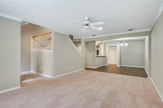 spare room featuring carpet floors, ceiling fan with notable chandelier, visible vents, and ornamental molding