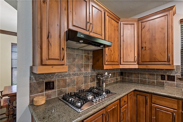 2409 Stone Castle Cir, College Station, TX 77845 - kitchen with under cabinet range hood, stainless steel gas stovetop, decorative backsplash, and brown cabinetry