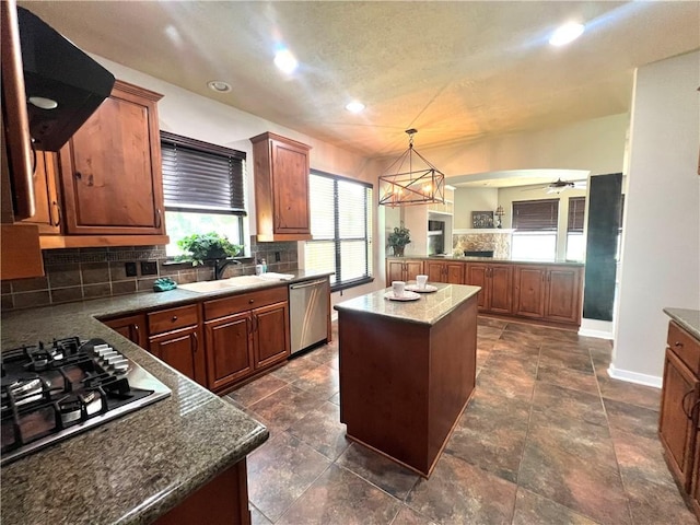 2409 Stone Castle Cir, College Station, TX 77845 - kitchen with appliances with stainless steel finishes, a sink, a kitchen island, tasteful backsplash, and baseboards