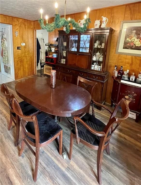 dining space featuring hardwood / wood-style floors, a textured ceiling, and wood walls